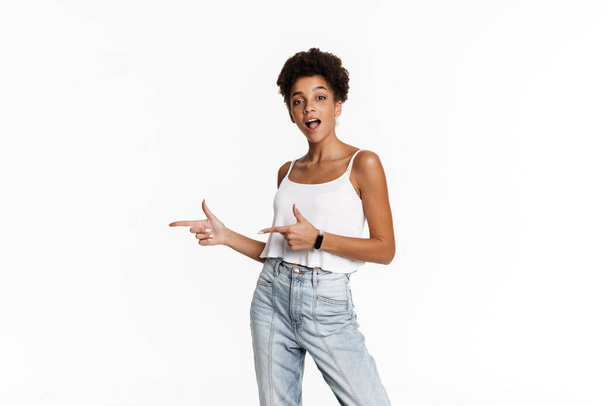 Young black surprised woman in tank top pointing fingers aside isolated over white background - Fotoğraf, Görsel