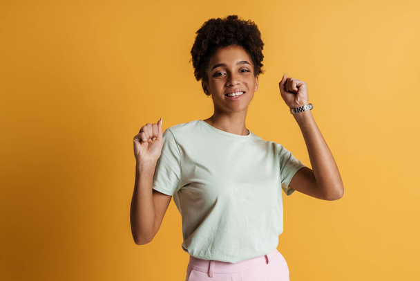 Young black woman laughing and gesturing at camera isolated over yellow background - Foto, Imagen