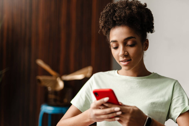 Young black woman using mobile phone while sitting at home - Photo, Image