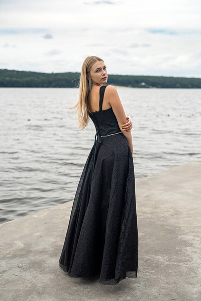 elegáns szőke nő egy divat fekete éjszakai ruha közelében tó, életmód - Fotó, kép
