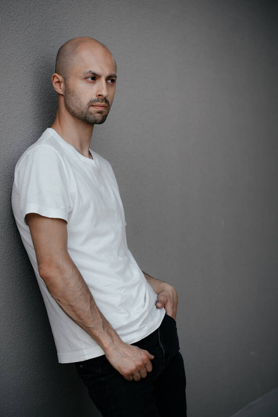 Bild eines gutaussehenden glatzköpfigen Mannes in einem weißen T-Shirt auf grauem Hintergrund. - Foto, Bild