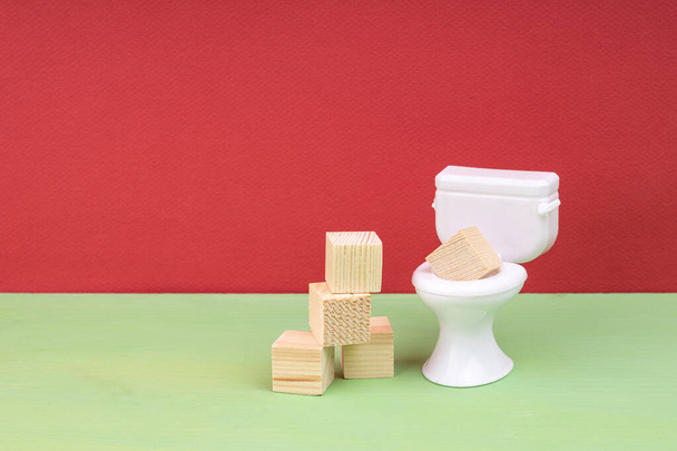houten blokjes naast een wit toilet. obstructie of blokkades in het sanitair - Foto, afbeelding