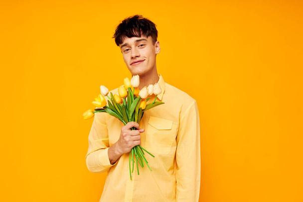 handsome guy in yellow glasses with a bouquet of flowers yellow background unaltered - Foto, immagini