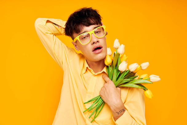 A young man in yellow glasses with a bouquet of flowers holiday unaltered - Foto, Imagen