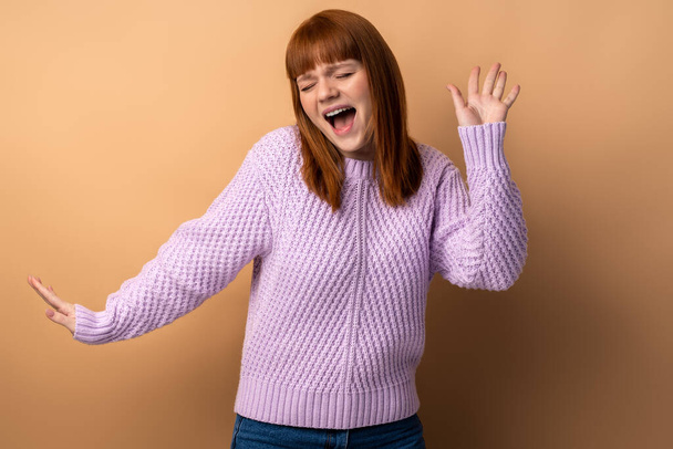 I am champion. Portrait of victorious delighted happy ginger woman raising hands, shouting for joy, screaming celebrating win success, thrilled emotions. Indoor studio shot isolated  - Fotó, kép