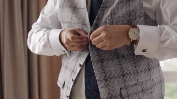 Buttoning jacket with hands close up, man in suit fastens buttons on his jacket preparing to go out - Footage, Video