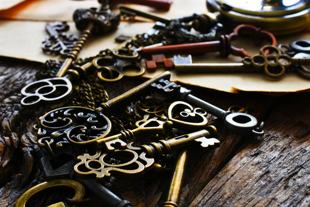 A low angle image of several small vintage keys with a gold colored pocket watch.  - Фото, изображение