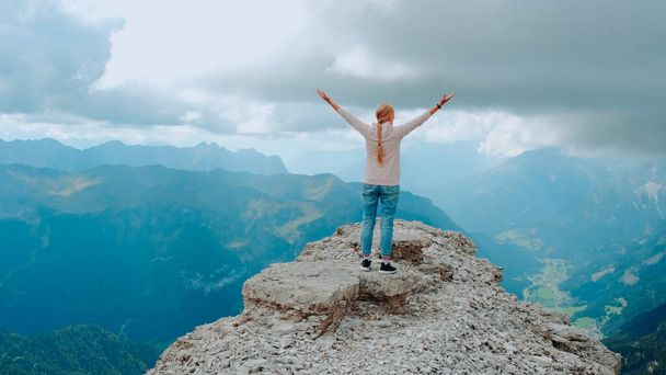 Jonge vrouw met uitgestrekte armen genietend van de schoonheid van de natuur op bergrots - Foto, afbeelding