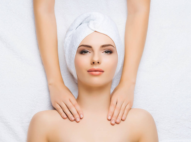 Young and healthy woman gets massage treatments for face, skin and neck in the spa salon. Health, wellness and rejuvenation concept. - Foto, immagini