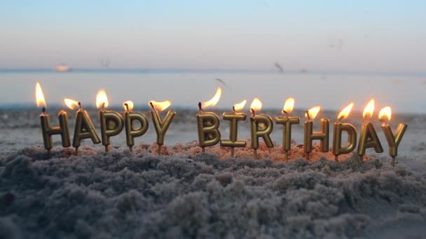 Candle Letters Gelukkige verjaardag branden op de achtergrond van wazige zee golven op het strand - Video
