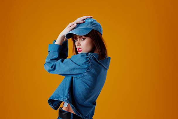 Portrait of a charming lady in a cap and denim jacket posing color background unaltered - Photo, Image