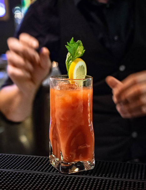 un barman apportant la touche finale en ajoutant la garniture à un cocktail de jus de tomate fraîchement préparé à base d'alcool et de jus de tomate  - Photo, image