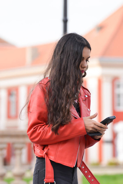 TIMISOARA, ROMANIA - March 15, 2018, Piata Unirii square: brunette woman wearing a red leather jacket is walking on the street - Valokuva, kuva