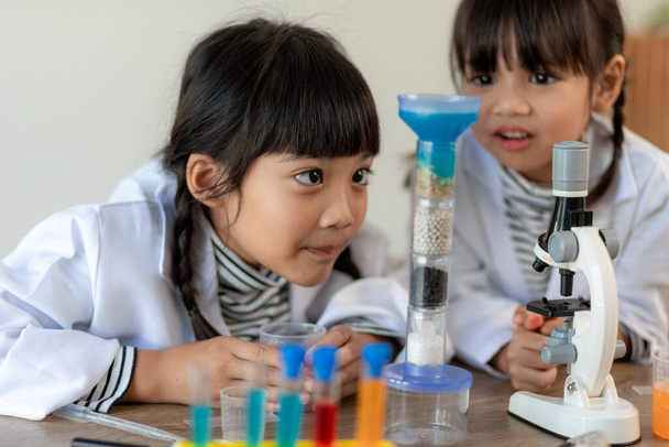 εκπαίδευση, επιστήμη, χημεία και παιδιά έννοια - τα παιδιά ή τους μαθητές με δοκιμαστικό σωλήνα καθιστώντας πείραμα στο σχολικό εργαστήριο - Φωτογραφία, εικόνα