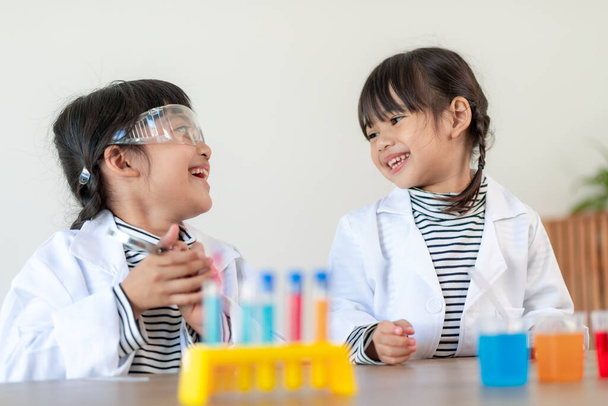 onderwijs, wetenschap, scheikunde en kinderen concept - jonge geitjes of studenten met reageerbuis maken experiment op school laboratorium - Foto, afbeelding