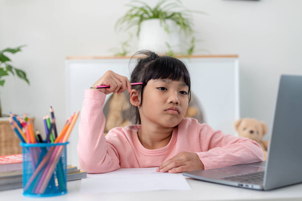 Das unglückliche kleine kaukasische Mädchen, das zu Hause am Tisch sitzt, fühlt sich faul und unmotiviert bei den Hausaufgaben. Verstört verzweifelte kleine 7s Kind bereiten Schulaufgaben, lernen Lernen mit Büchern. Bildungskonzept. - Foto, Bild