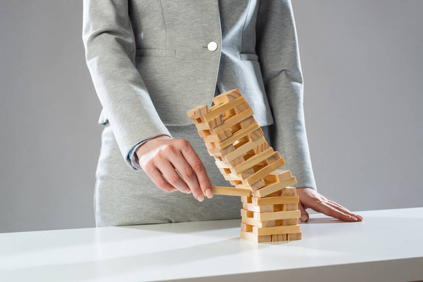 Businesswoman removing wooden block from tower - Photo, Image