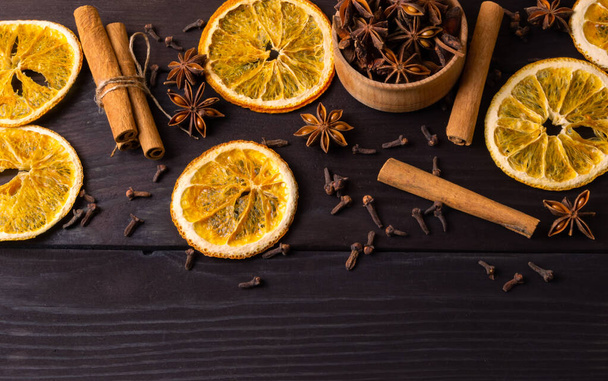 Πάνω άποψη Αποξηραμένη φέτα πορτοκαλιού, ξυλάκια κανέλας και γλυκάνισο σε σκούρο ξύλινο φόντο. Παραδοσιακή Χριστουγεννιάτικη σύνθεση. Επίπεδη - Φωτογραφία, εικόνα