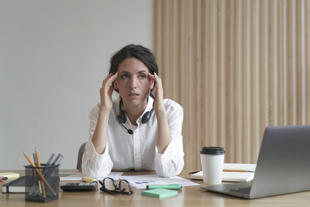 Розчарована бізнес-леді відчуває себе втомленою, сидячи на посаді, страждаючи від головного болю на роботі
 - Фото, зображення