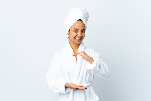Jovem mulher em roupão de banho sobre fundo branco isolado segurando copyspace imaginário na palma da mão para inserir um anúncio - Foto, Imagem