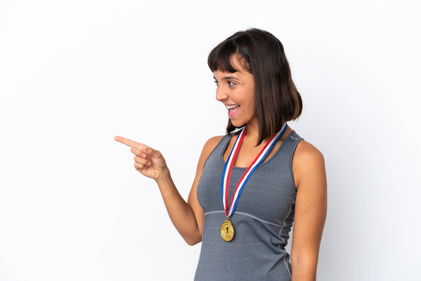 Young mixed race woman with medals isolated on white background pointing finger to the side and presenting a product - Photo, Image