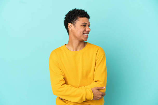 Young African American man isolated on blue background looking to the side and smiling - Photo, image