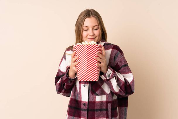 Teenager ukrajinské dívka izolované na béžové pozadí drží velký kbelík popcornů - Fotografie, Obrázek