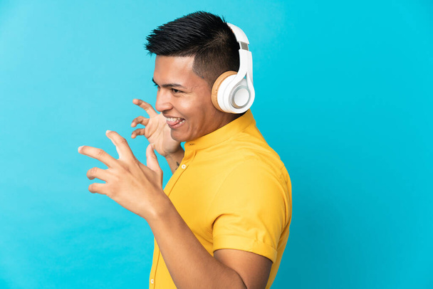 Young Ecuadorian man isolated on blue background listening music and dancing - Fotoğraf, Görsel