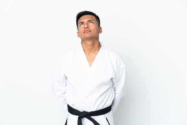 Mladý ekvádorský muž dělá karate izolované na bílém pozadí a vzhlíží - Fotografie, Obrázek