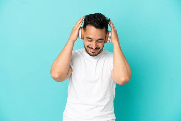 Giovane uomo caucasico isolato su sfondo blu ascoltare musica - Foto, immagini