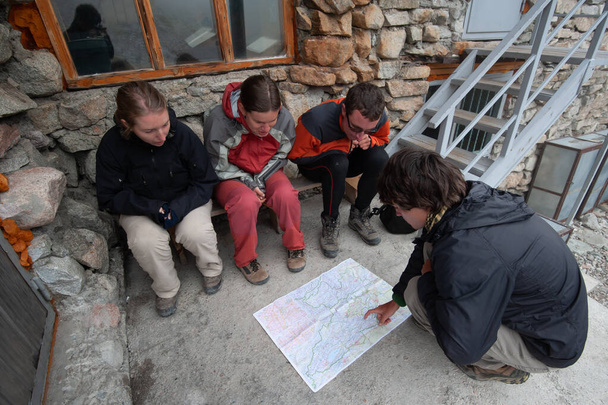 Group of trekkers backpackers consulting map. Navigation. Orientation in mountains. Ala Archa Alpine National Park Landscape near Bishkek, Tian Shan Mountain Range, Kyrgyzstan, Central Asia. - 写真・画像