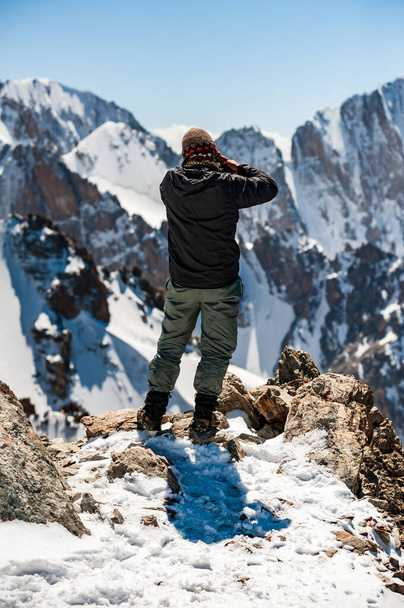 Joven hombre caminante fotógrafo tomando fotos con cámara en la parte superior del pico Pik Uchitel. Parque Nacional Alpino Ala Archa Paisaje cerca de Biskek, Cordillera Tian Shan, Kirguistán, Asia Central. - Foto, imagen