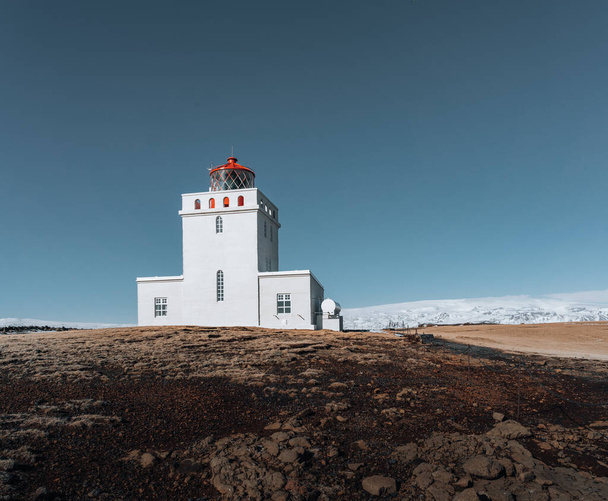 Panoramic image of the lighthouse of Cape Dyrholaey with snow and early morning light with blue sky. winter in Iceland. - Photo, Image