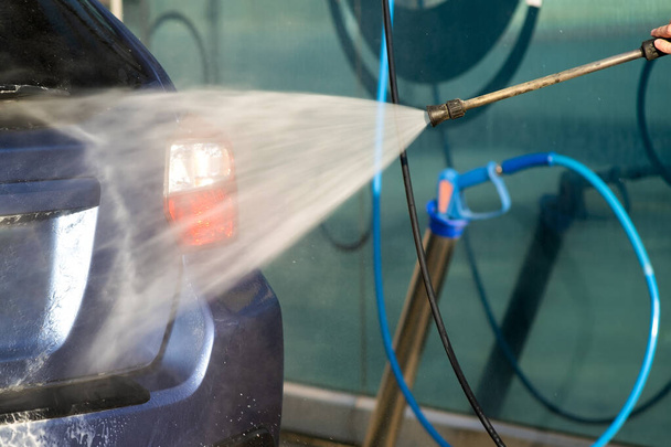 Primer plano del conductor masculino que lava su coche con chorro de agua de alta presión sin contacto en el auto servicio de lavado de coches - Foto, Imagen