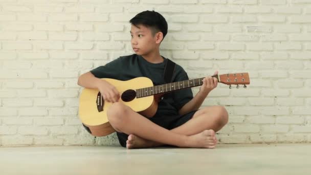 Tiener jongen spelen gitaar in het huis genieten. - Video
