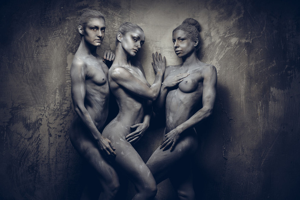 Naked sportive women painted in grey color posing over grey wall - Fotoğraf, Görsel