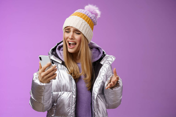 Bothered complaining dissatisfied cute blond girl yelling stupid smartphone standing unhappy recording audio message whining yelling mobile phone upset, standing purple background - Fotografie, Obrázek
