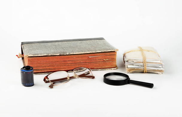 Albums with old family photos, glasses and a magnifying glass on a white background. - Foto, Imagem