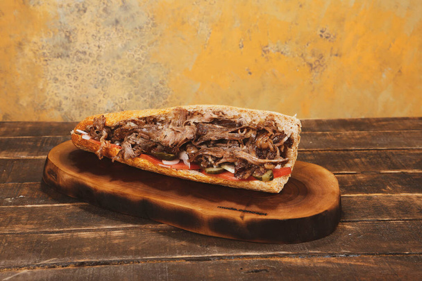 O Doner Kebab está deitado na tábua de corte. Shawarma com carne, cebolas, salada está em uma velha mesa de madeira escura - Foto, Imagem