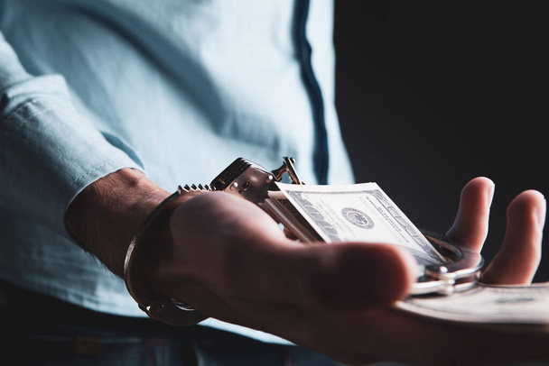 a man in handcuffs holds money. concept crime - Фото, зображення