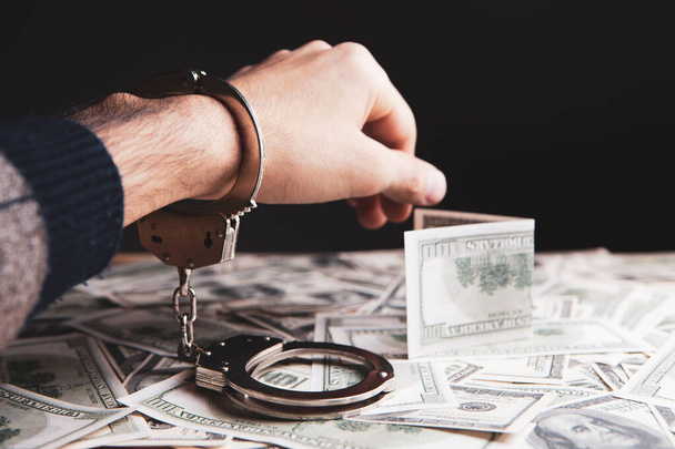 handcuffed at the table with money - Foto, afbeelding