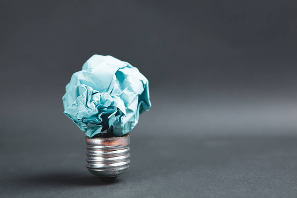 crumpled paper light bulb on black background - Foto, afbeelding