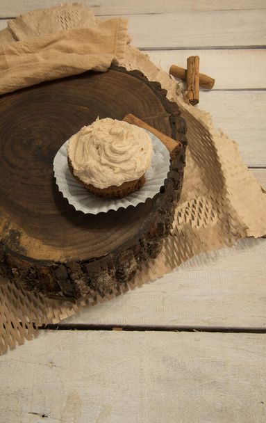 Single, iced cupcake. Woodslice, whitewash board table with crinkled,  textured paper. - Zdjęcie, obraz
