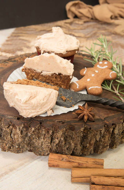 Gingerbread cupcake halved sitting on a wood slice. Gingerbread man, cinnamon sticks, star anise, rosemary sprigs. - Zdjęcie, obraz