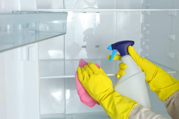 Женщина моет холодильник дезинфицирующими средствами крупным планом.. - Фото, изображение