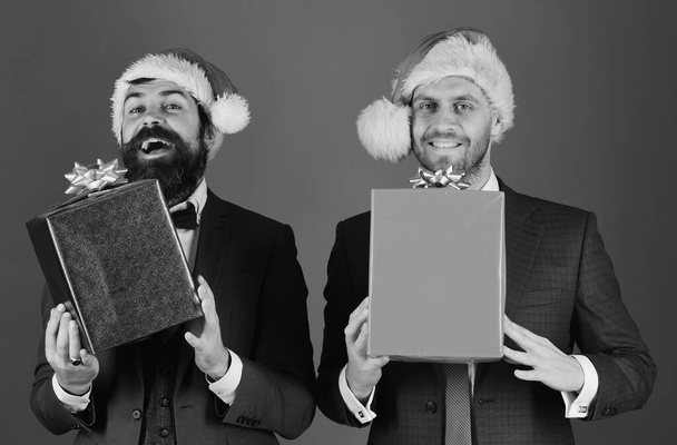 Men in smart suits and Santa hats on blue background. - Foto, imagen