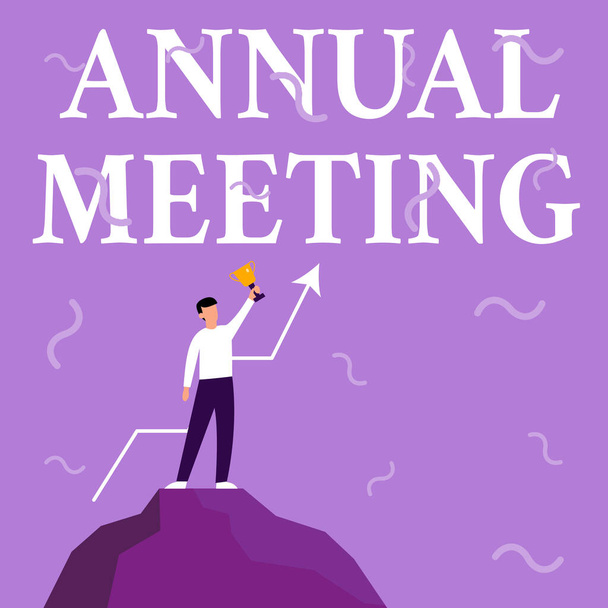 Handwriting text Annual Meeting. Conceptual photo scheduled annually for the discussion of the business future Businessman Drawing Standing On Big Rock Proudly Holding Trophy. - Фото, изображение