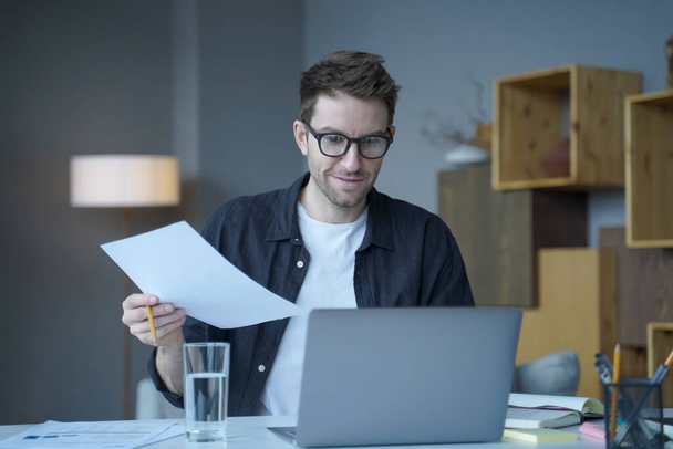 Pewny siebie doradca finansowy człowieka w okularach pracuje zdalnie online w nowoczesnym biurze - Zdjęcie, obraz