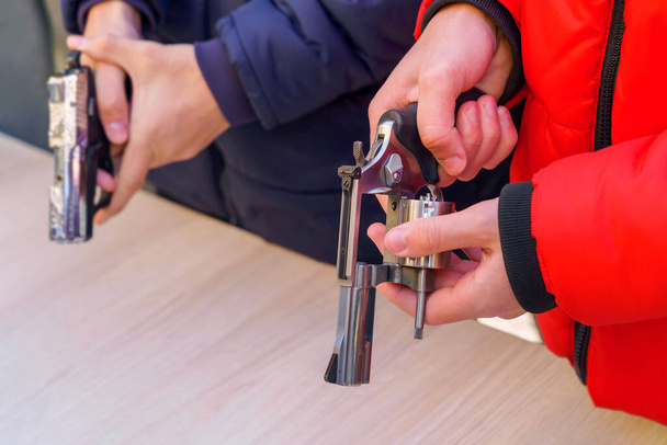 Revolver in the hands of a young man, selective focus. Reloading weapons. Shooting training. Rules for keeping and carrying firearms. Background with copy space - Foto, Bild