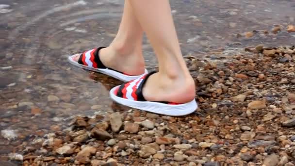 pies de una chica en chanclas rojas entran en el agua en un día soleado caliente, cámara lenta - Metraje, vídeo